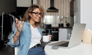 A woman smiles as she video chats on her laptop.