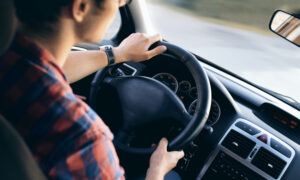 A young man behind the wheel of a vehicle