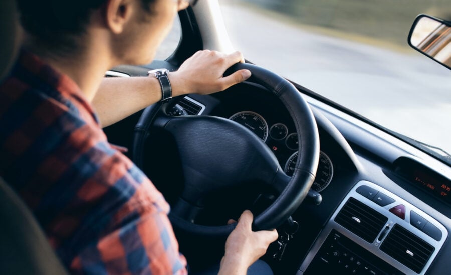 A young man behind the wheel of a vehicle