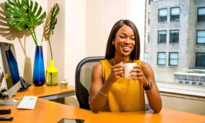 A smiling financial advisor sits behind her desk, holding a mug