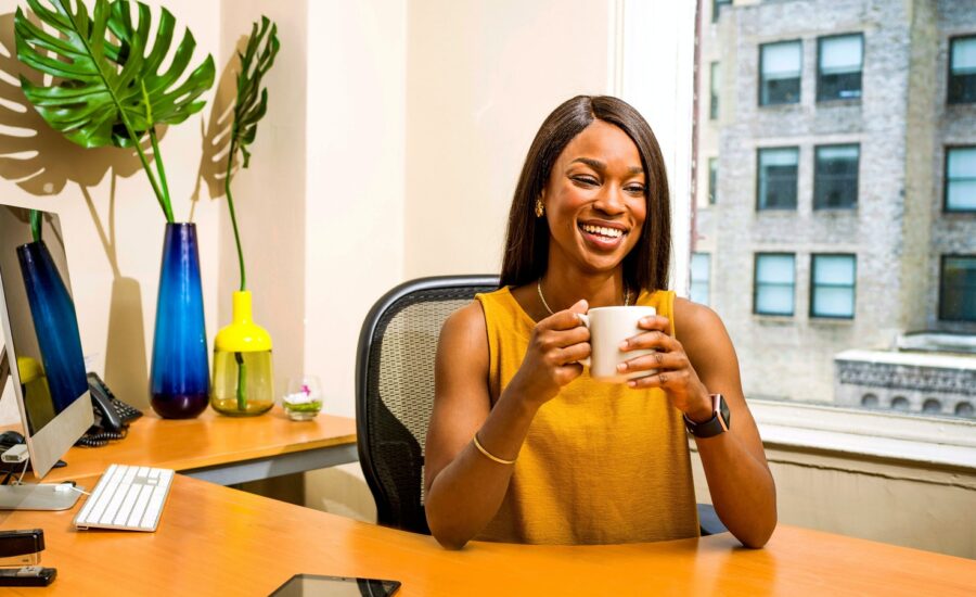 A smiling financial advisor sits behind her desk, holding a mug