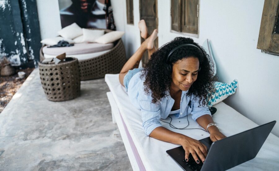 A woman is seen working on a laptop and laying down