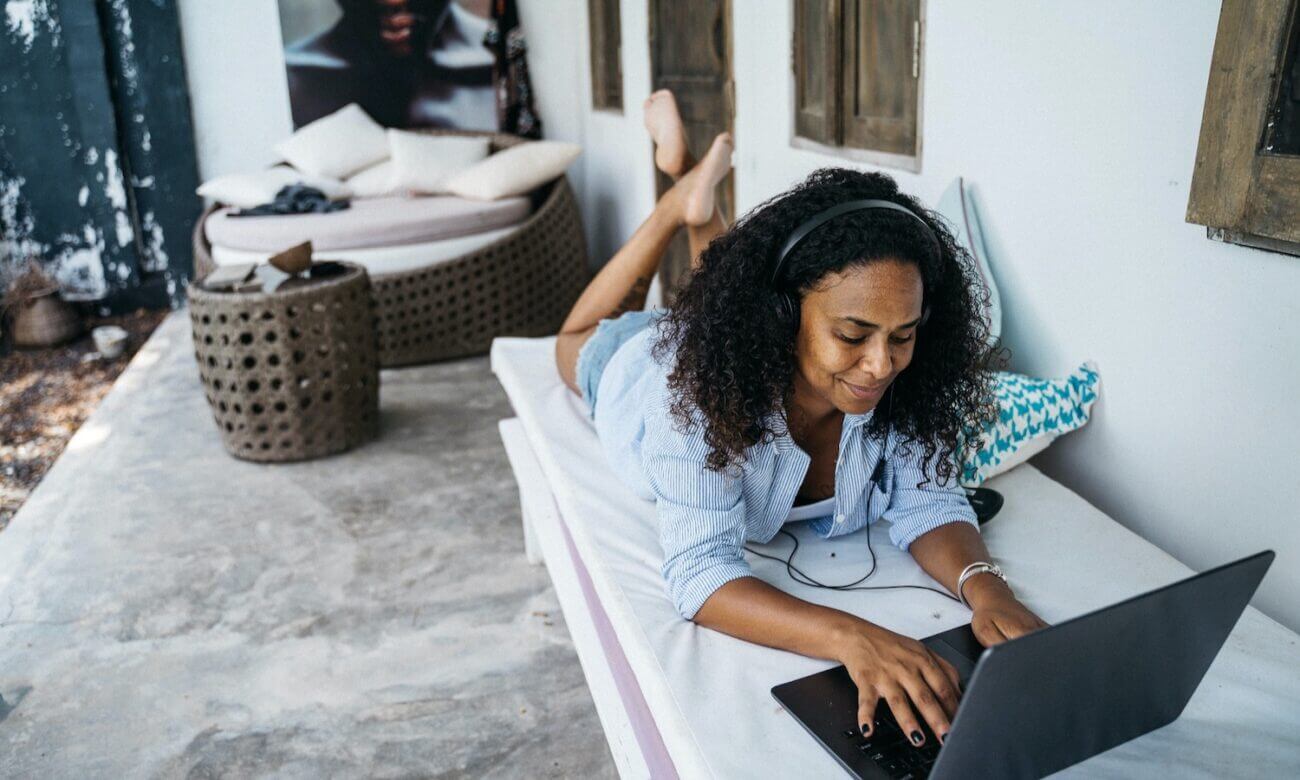 A woman is seen working on a laptop and laying down