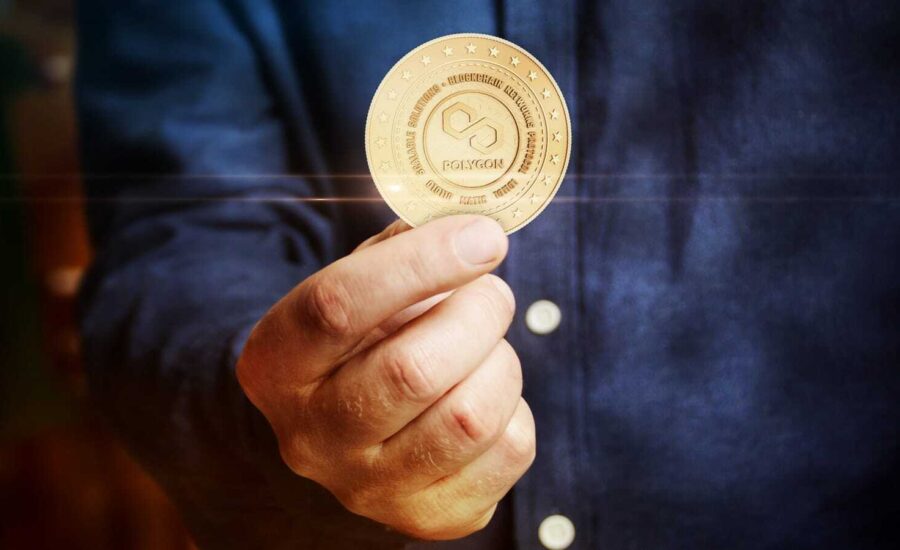 A hand holds a gold coin with the Polygon logo.