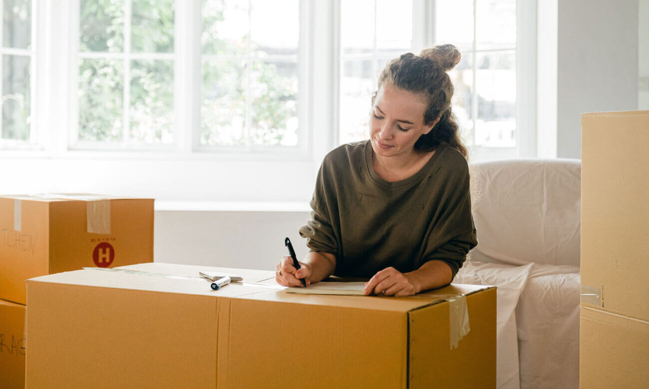 A woman is seen writing on a box