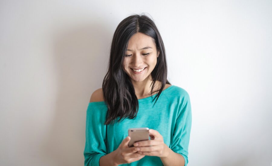 A smiling young woman looks down at her smartphone