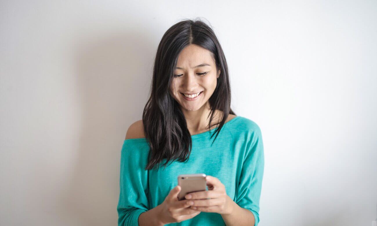 A smiling young woman looks down at her smartphone