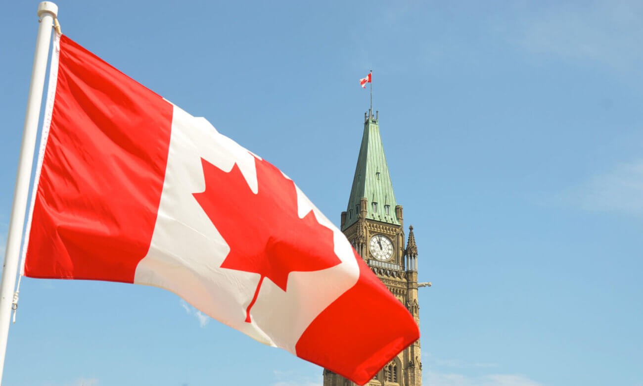 A Canadian flag stands high in front of a federal building in Ottawa