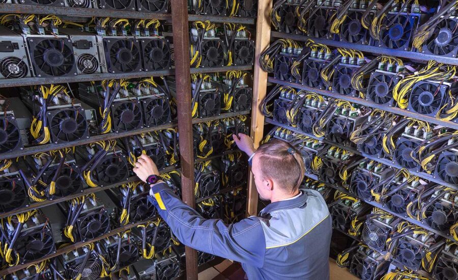 A young man tends to a shelf of crypto mining computers