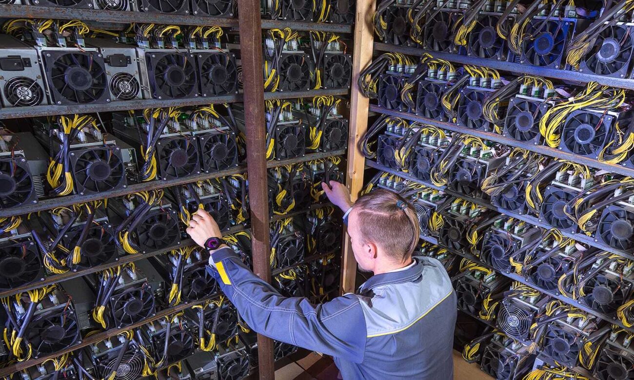 A young man tends to a shelf of crypto mining computers