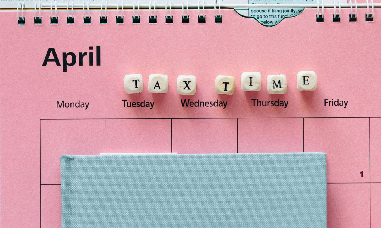A ring-spine calendar for April, with a note book, and block lettering spelling out the words "tax time".