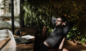 At a coffee shop, a man sits back at his computer, looking impressed with himself.