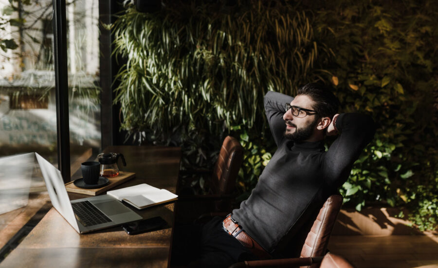 At a coffee shop, a man sits back at his computer, looking impressed with himself.