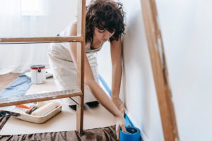 A woman prepares a wall to be painted