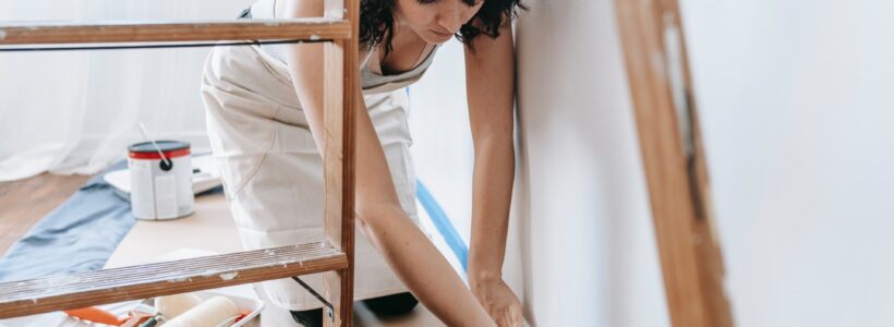 A woman prepares a wall to be painted