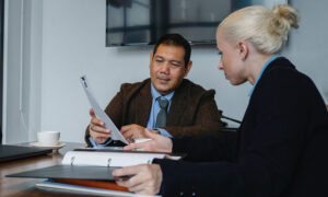 A man with a wedding band is meeting with a lawyer to go over will documents.