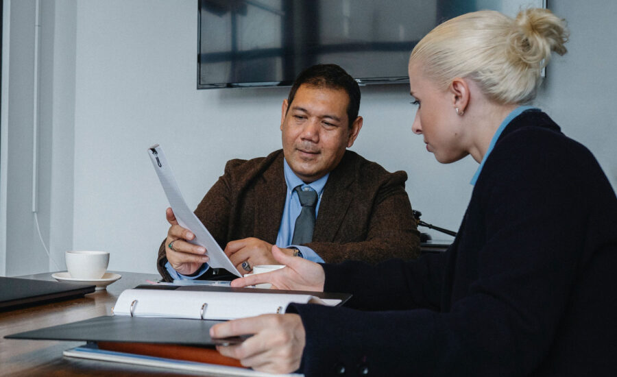 A man with a wedding band is meeting with a lawyer to go over will documents.