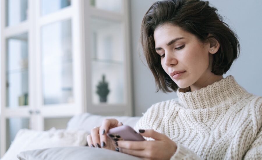 A woman looks sadly at her smartphone