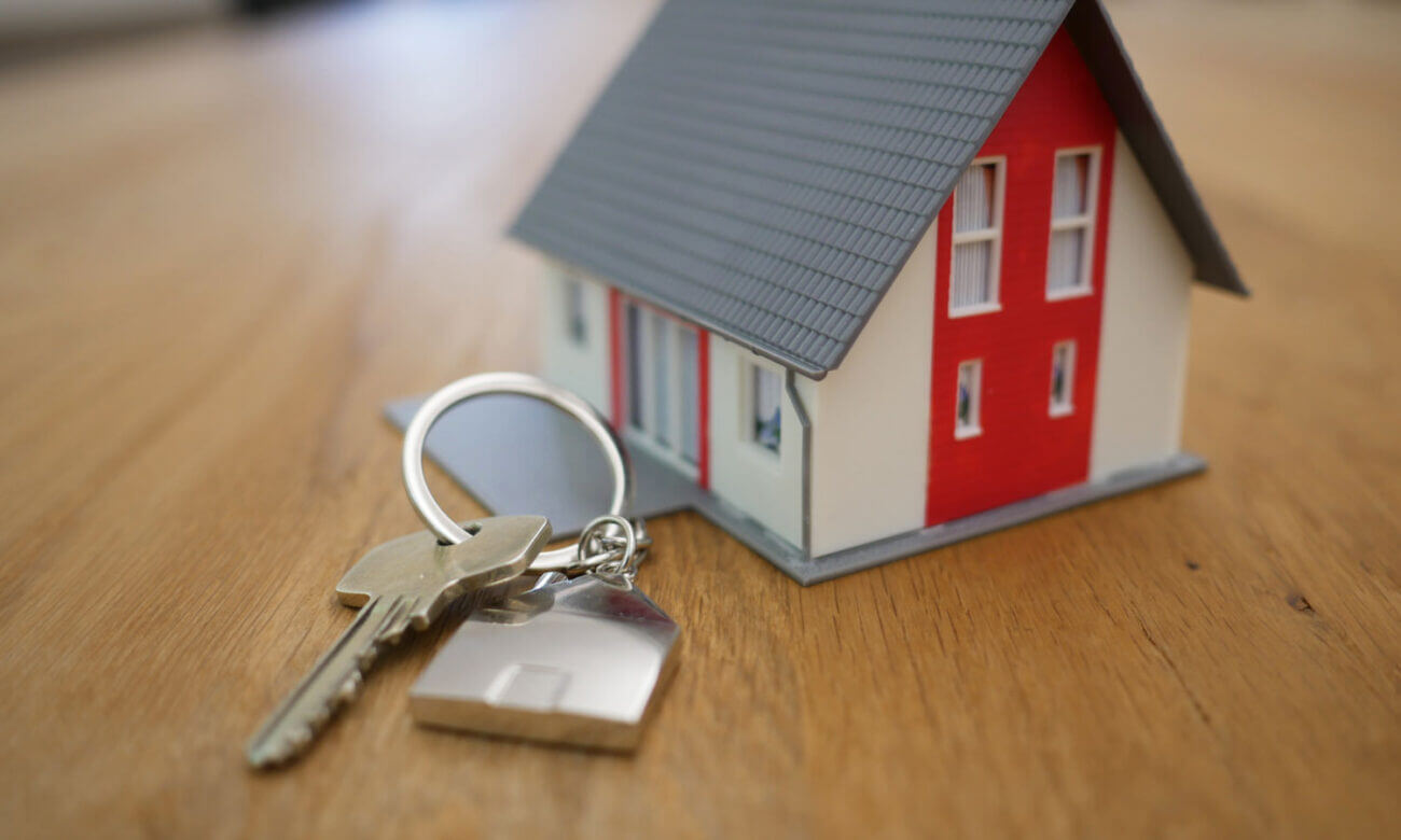a miniature house with an actual size set of keys, symbolizing