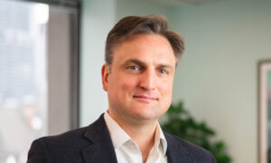 A headshot of Myron Genyk in his office, with the window behind him