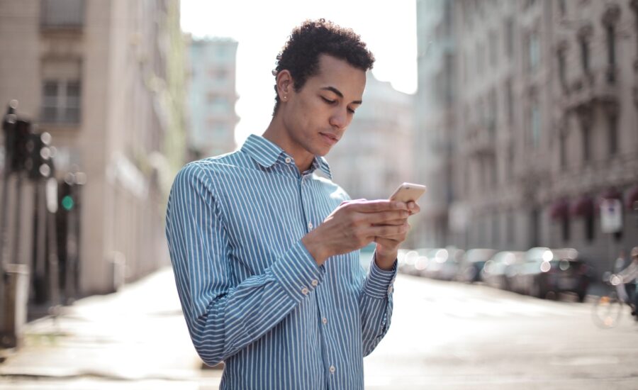 A young man on a sidewalk looking at his smartphone