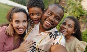 Mom, dad and two young kids smile at the camera