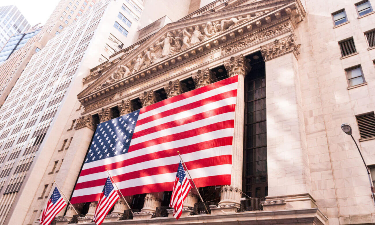 The outside of the NYSE, standing proud and tall, completely decorated with American flags.