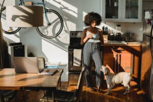 a young woman drinks coffee in a small apartment with dog