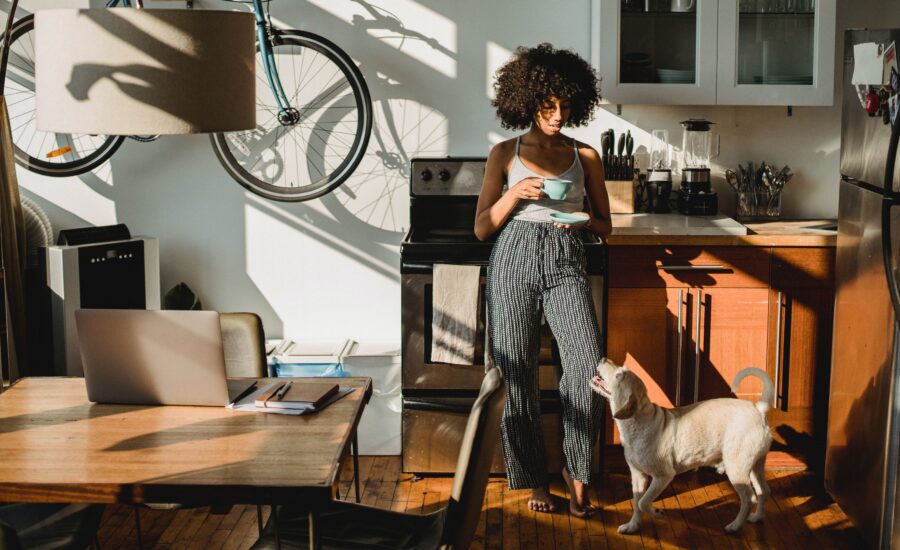 a young woman drinks coffee in a small apartment with dog