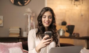 A young woman smiles as she looks at her phone, as she invests in ETFs for the first time.