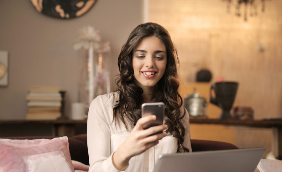 A young woman smiles as she looks at her phone, as she invests in ETFs for the first time.