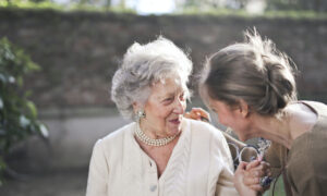 A woman in her 60s is greeting her mother with a hug.