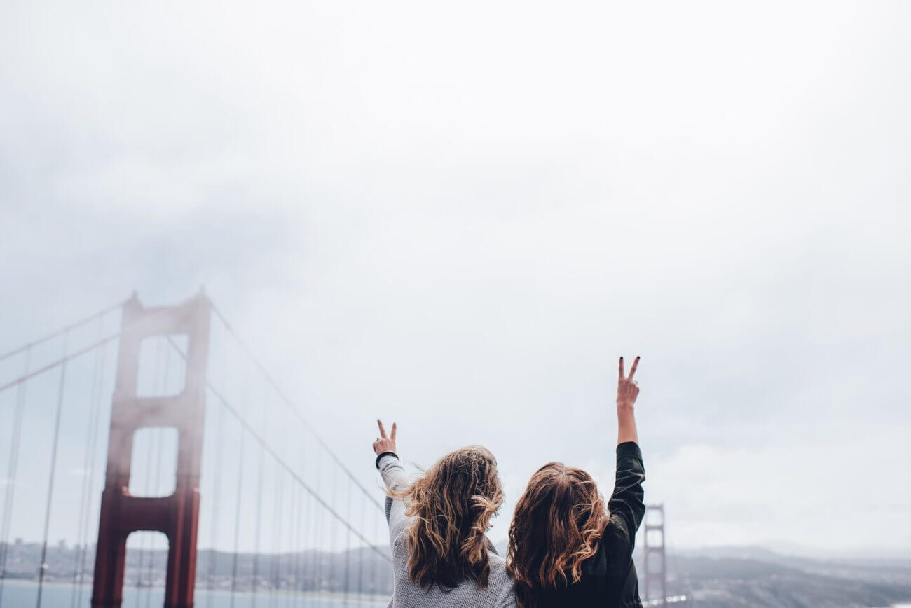 two women pose in front of the golden gate bridge
