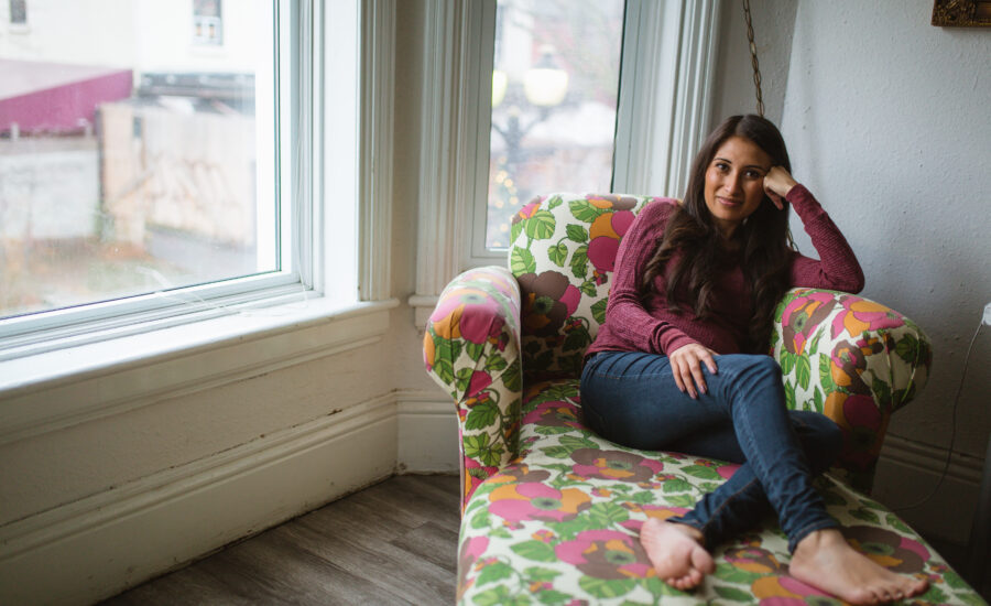 a woman sits in an armchair near a window