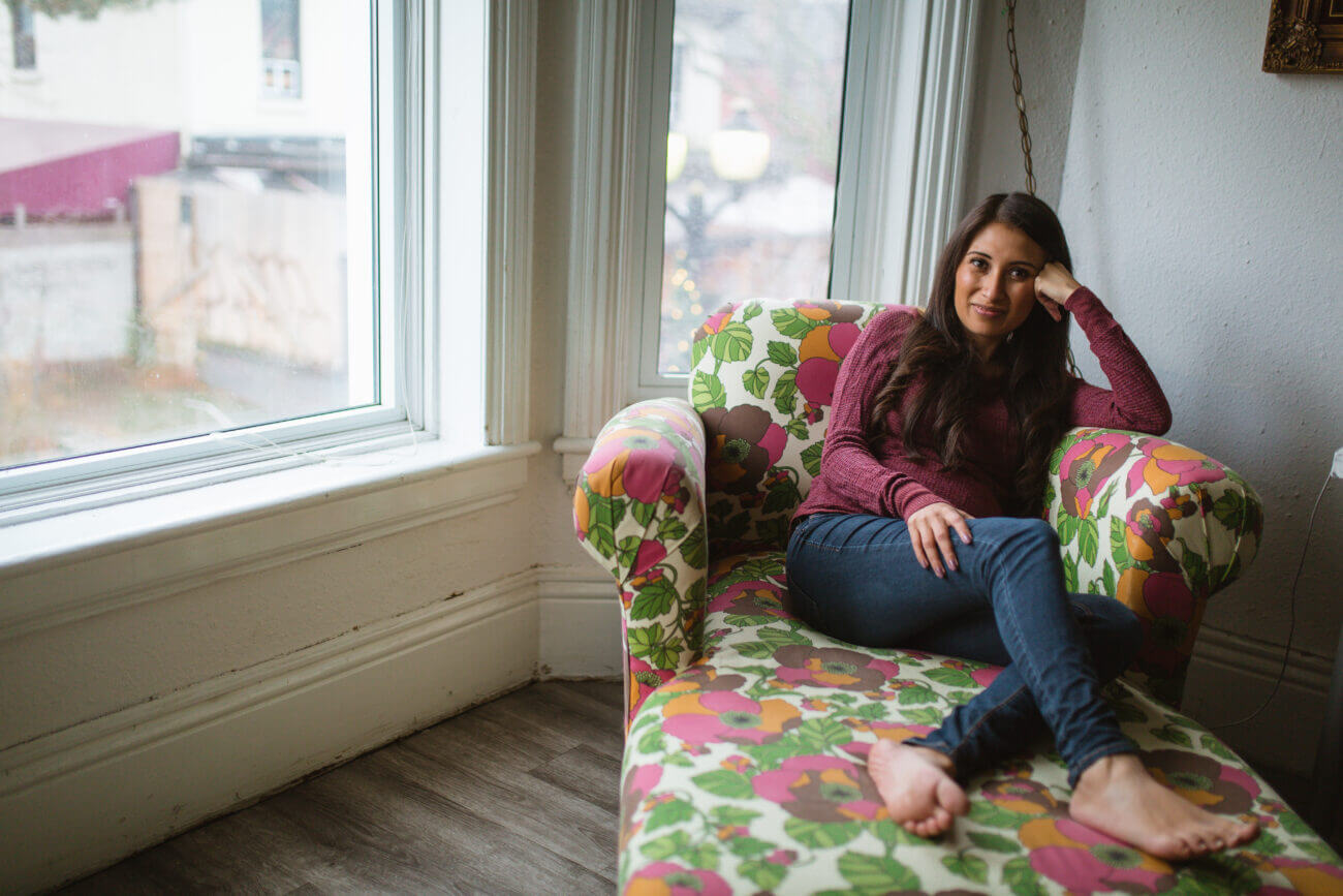 a woman sits in an armchair near a window