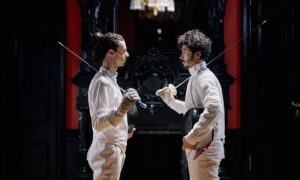 Two men in fencing gear stand facing each other.