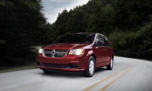 A red Dodge Caravan is seen driving on the road