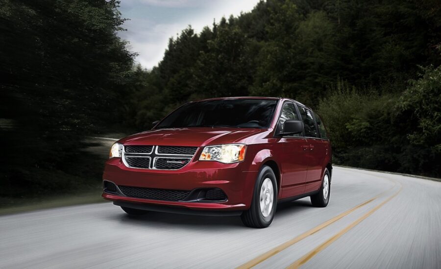 A red Dodge Caravan is seen driving on the road