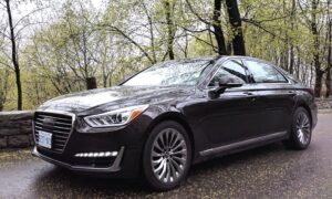 A black Genesis G90 driving on a road