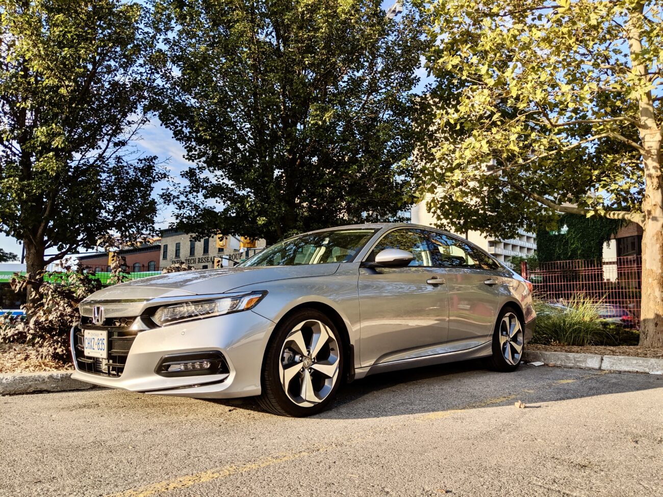 A silver Honda Accord in a parking lot surrounded by trees