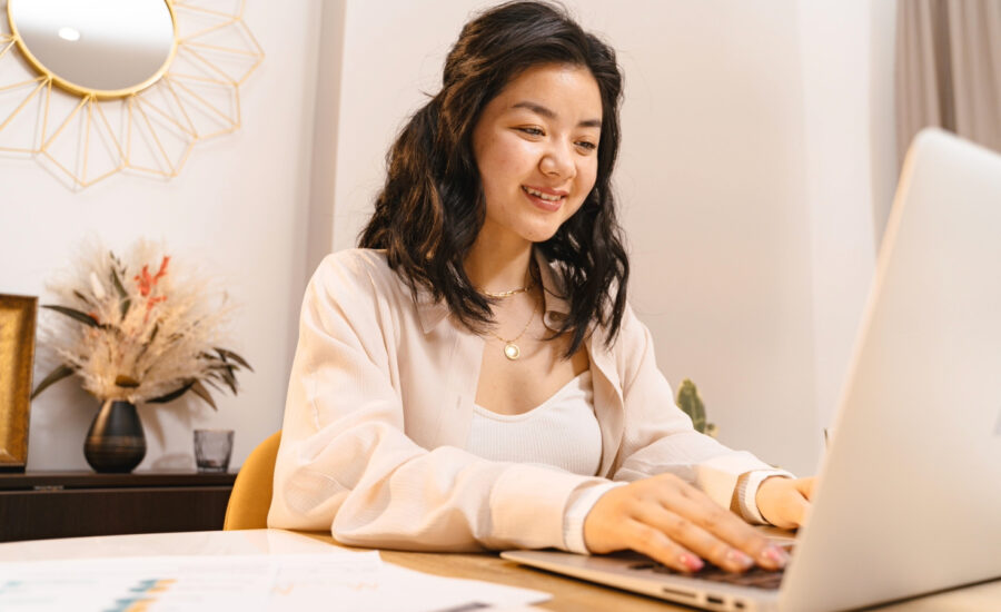 A woman is seen smiling at her laptop