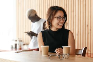 a young woman with glasses smiles in a cafe
