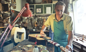 A man builds an acoustic guitar by hand in his workshop