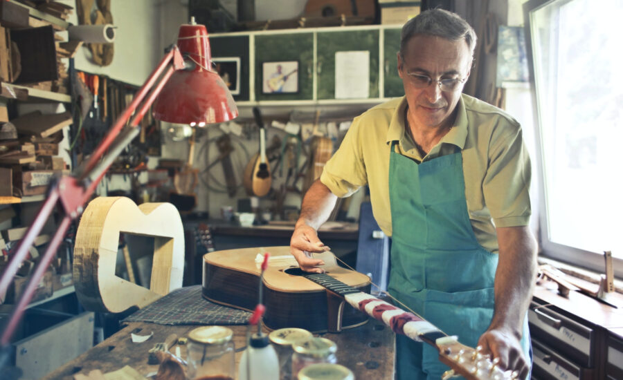 A man builds an acoustic guitar by hand in his workshop