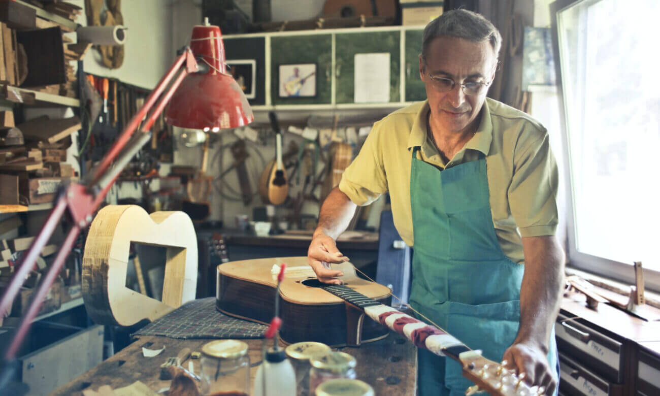 A man builds an acoustic guitar by hand in his workshop