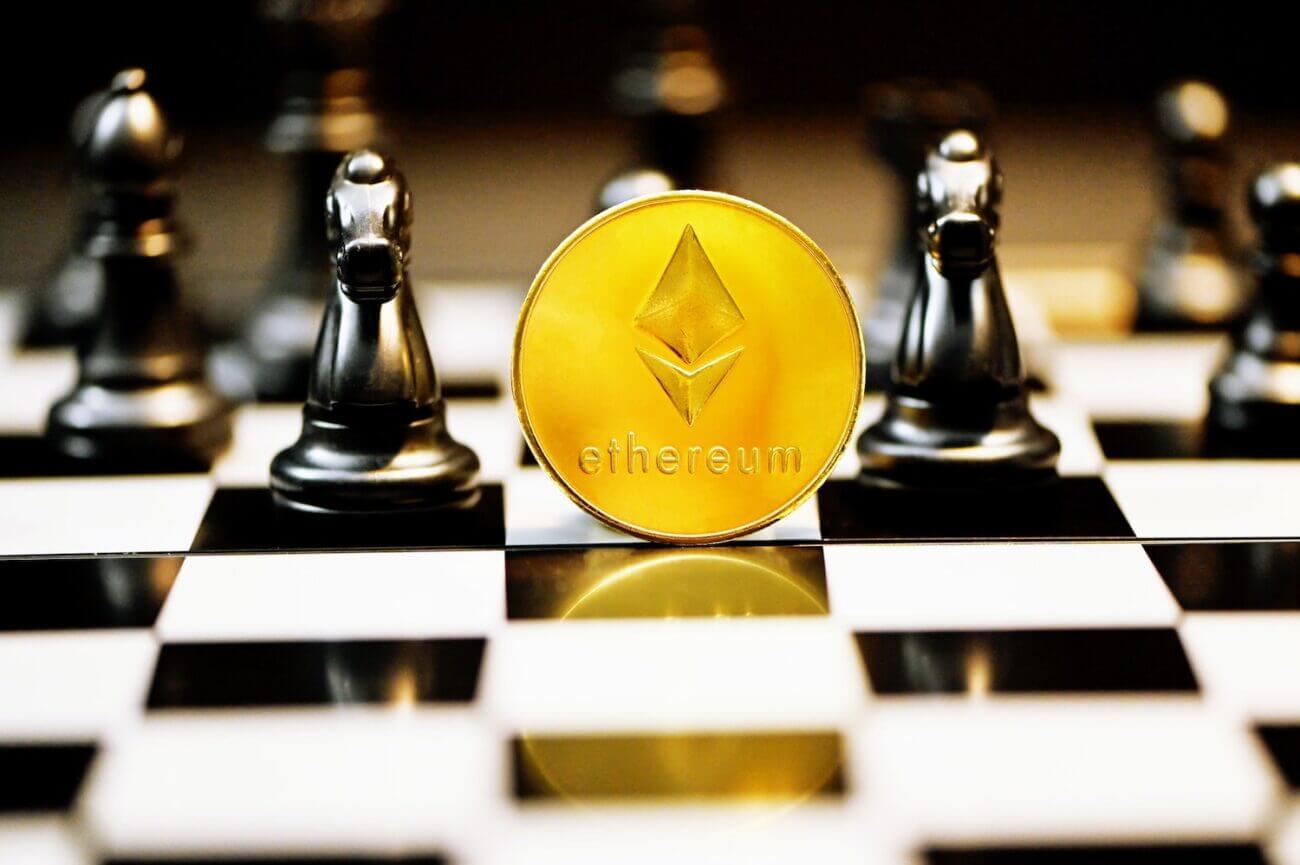 A gold coin with an Ethereum logo sits on a chess board