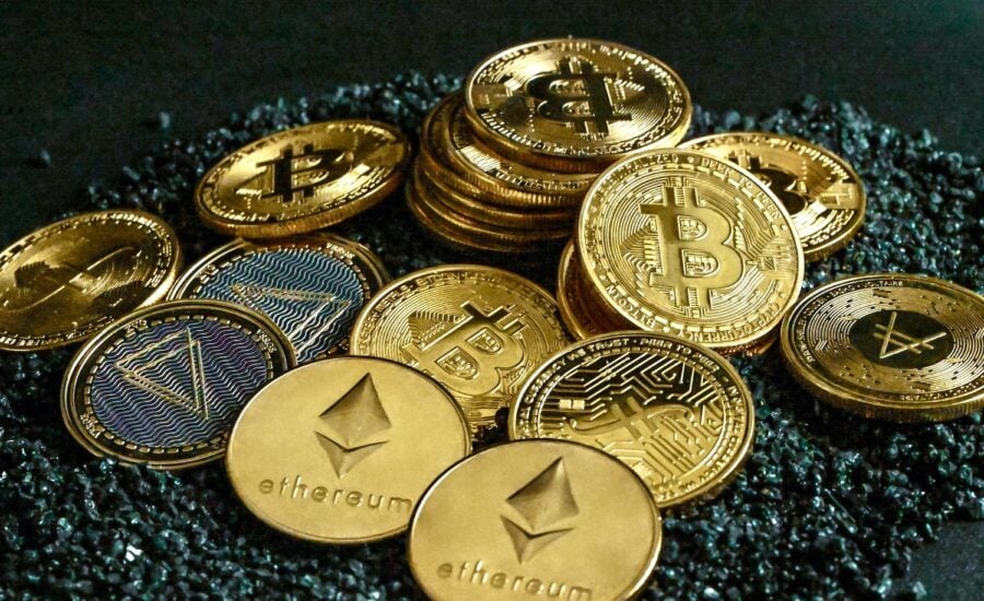 A pile of gold coins with different cryptocurrency logos