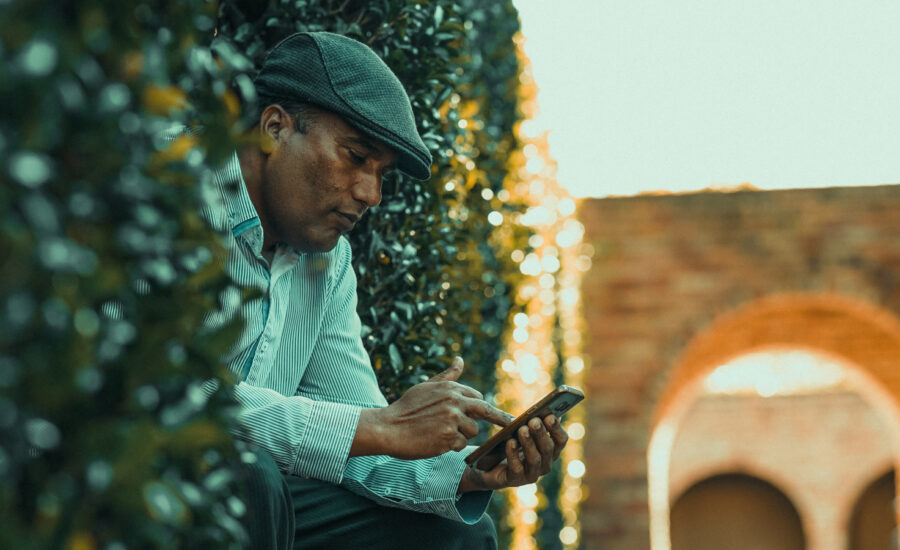 A man sits outside near hedges, contemplating transferring his home to his daughter's name