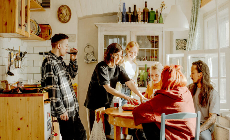 A young woman, who was just able to afford to live on her own, is hosting dinner to her friends in the kitchen of her new pad.