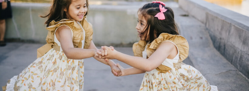 Young twin girls hold hands and dance, excited by their family's purchase of another home.